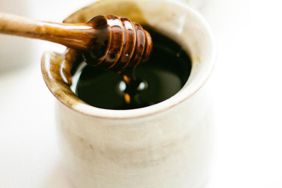 Dark raw honey on a wooden dipper